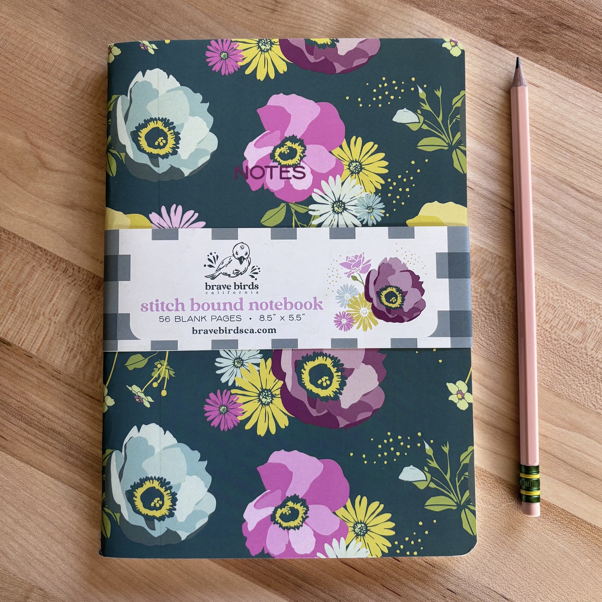 Blue and yellow and purple floral print notebook shown on a wood table with a pencil