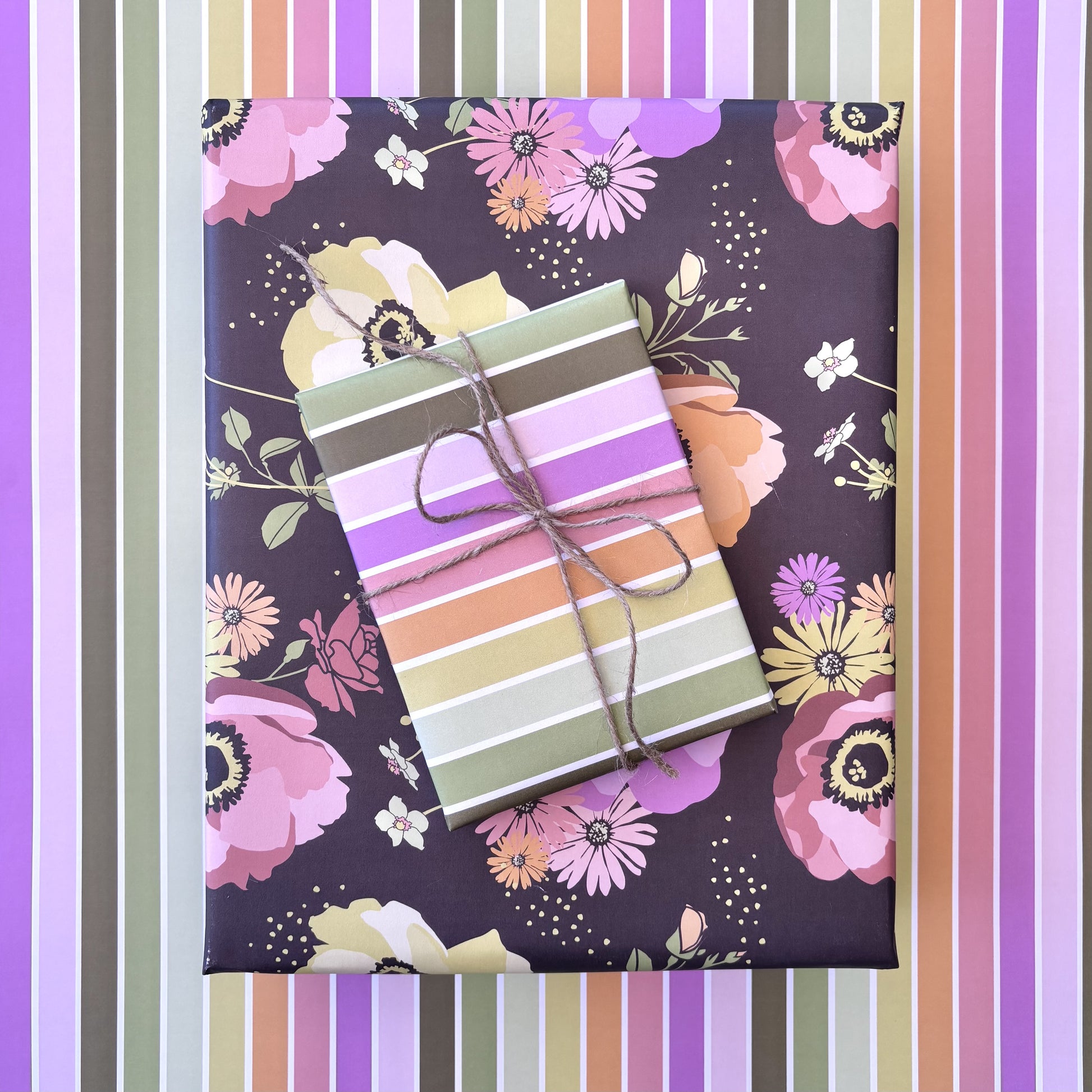 Gift box with striped paper on floral-patterned paper with colorful vertical stripes.