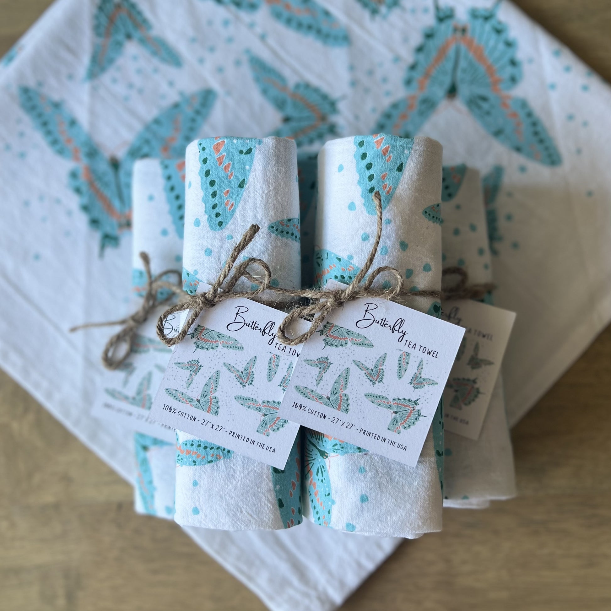 Rolled up stack of butterfly tea towels, tied with twine and hang tags