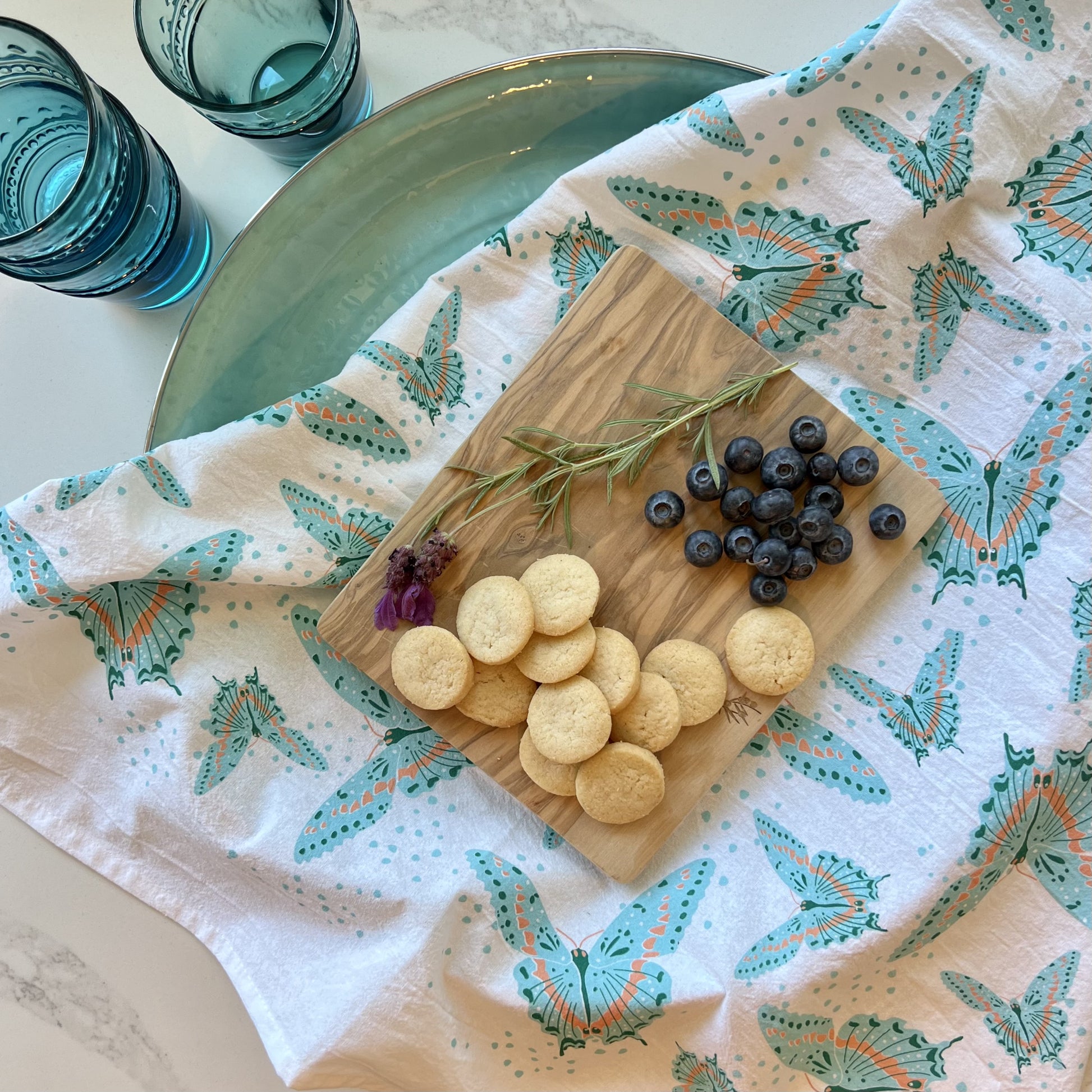 Butterfly Tea Towel styled with a wood plater, cookies, blueberries and lavender