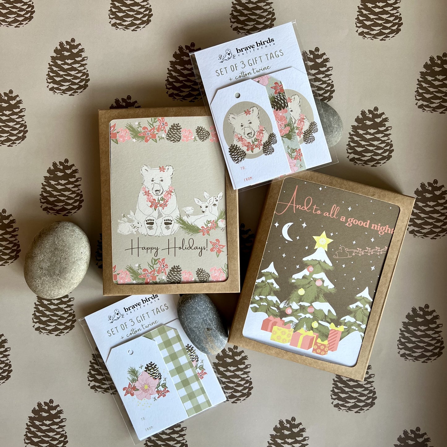 Stack of holiday stationery. Two boxed card sets and two packs of gift tags. All illustrated with forest scenes showing animals and a decorated tree.