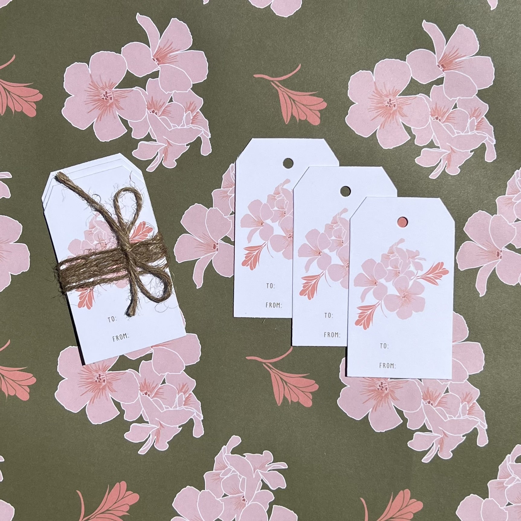 3 pack of gift tags wrapped with twine laid out on a sheet of coordinating wrapping paper