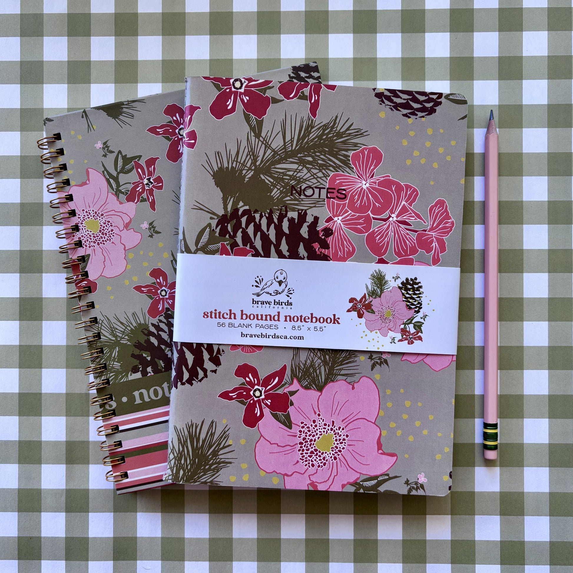 pink and green floral and stripe spiral notebook with pinecones under pink and green floral and stripe notebook with pinecones on green and white plaid background with pink pencil