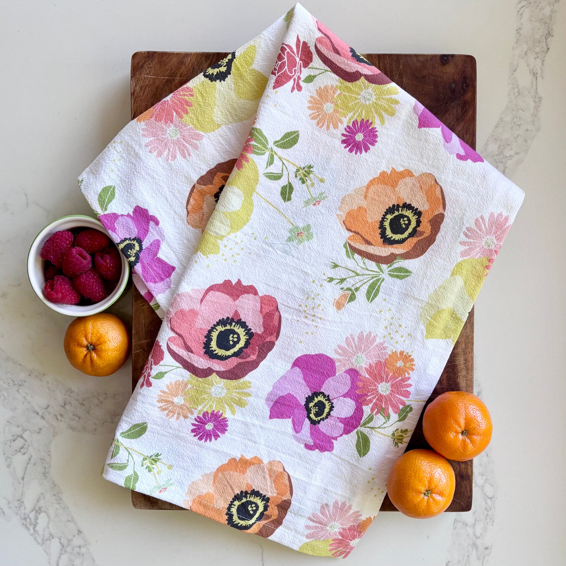 Floral towel on a wooden cutting board with fruits and berries