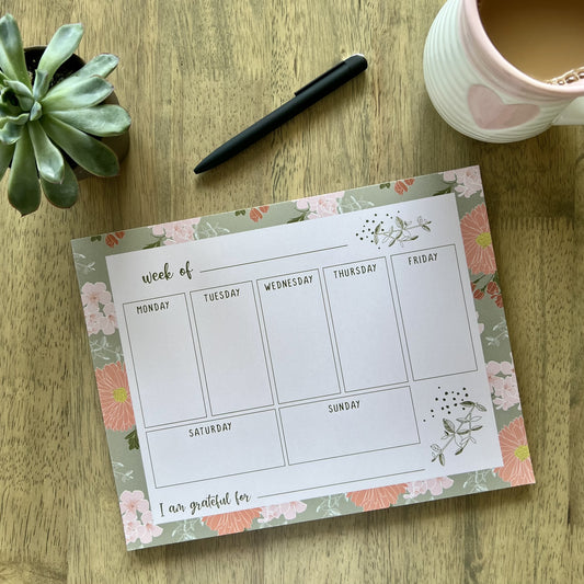 notepad with floral border, light pink writing area and a grid with boxes to write notes for each day of the week, plus a blank "I am grateful for" section at the bottom