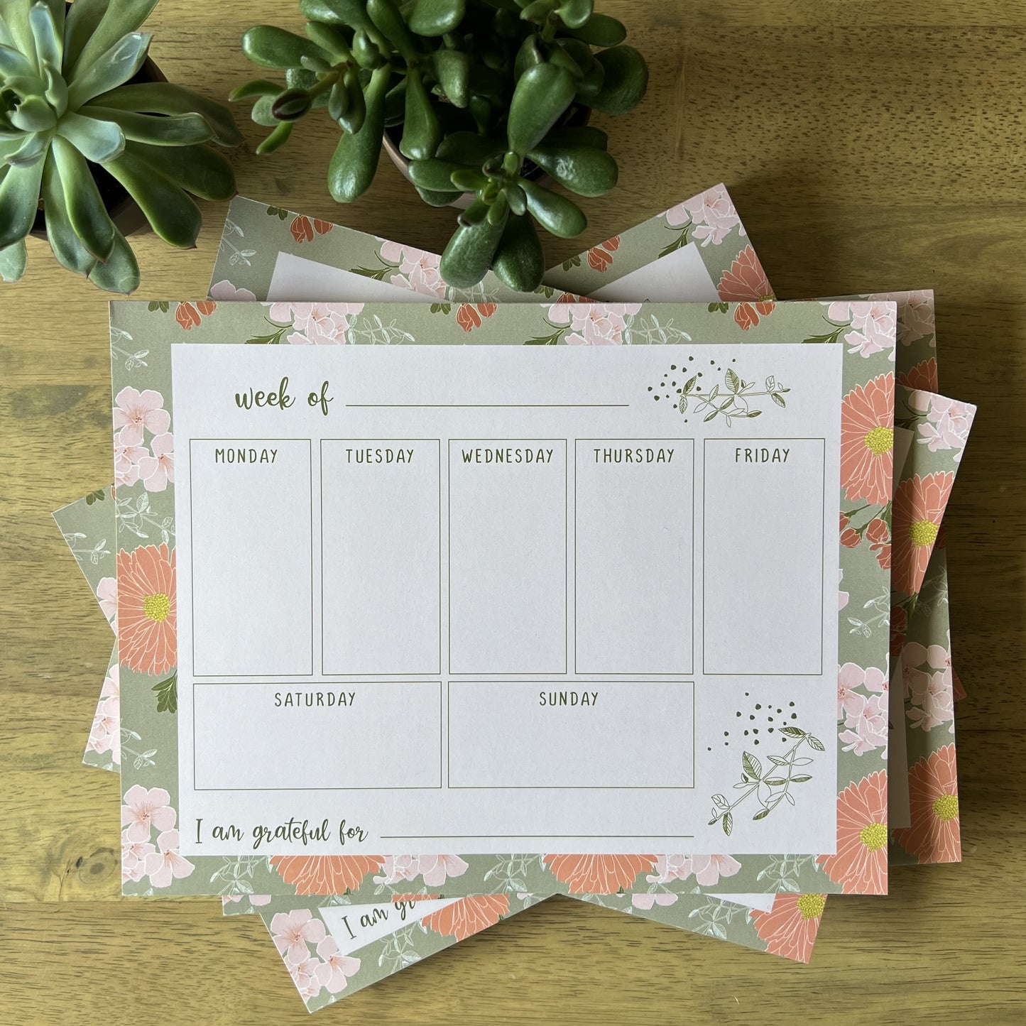 Weekly Planners styled in a pile with succulents on a wood table