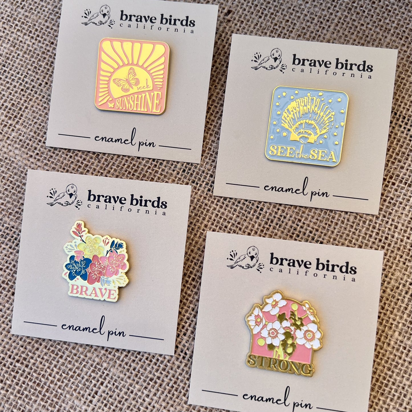 Set of four enamel pins with pastel colors accented with gold and various inspiring phrases