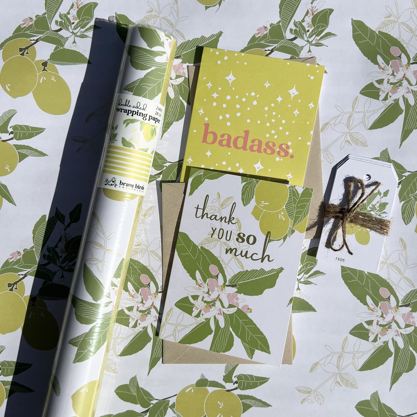 Lemon print wrapping paper, shown with a lemon print thank you card, a citron "badass" card, and lemon gift tags
