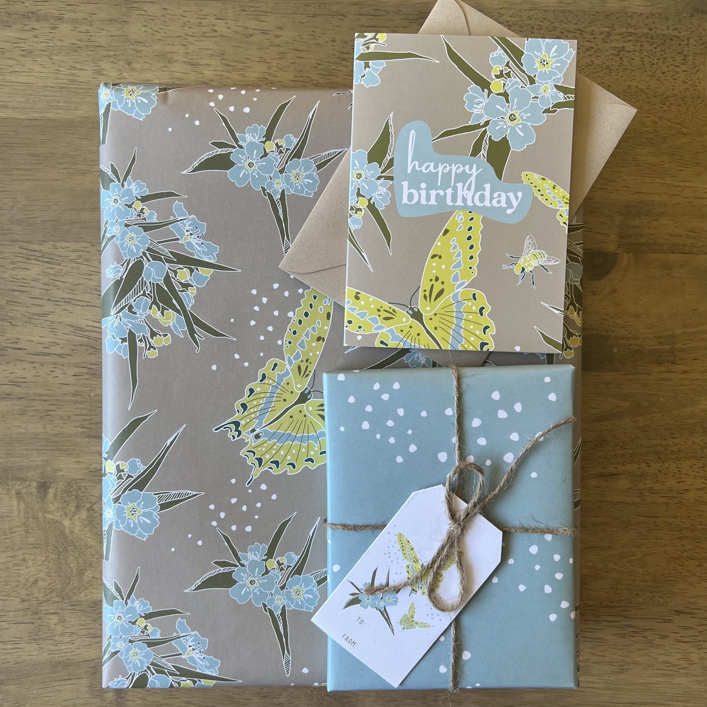 Box wrapped in khaki, blue and yellow butterfly floral print with a gift tag tied with twine and a matching greeting card
