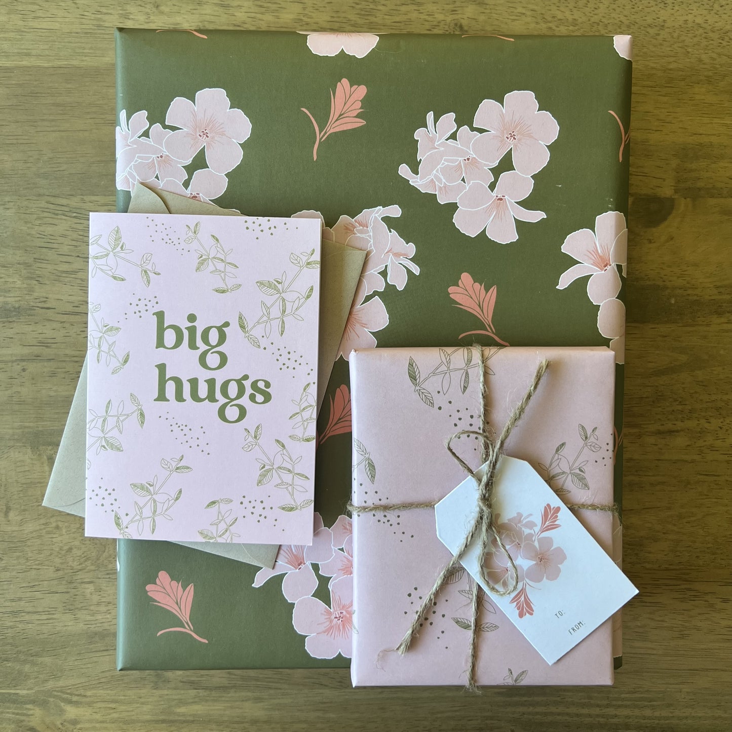 Box wrapped in pink & oplive floral wrapping paper with a gift tag tied with twine and a matching greeting card