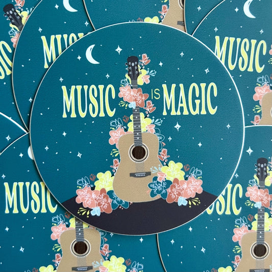 Pile of stickers featurign an illustration of a guitar draped in flowers and the words "music is magic"