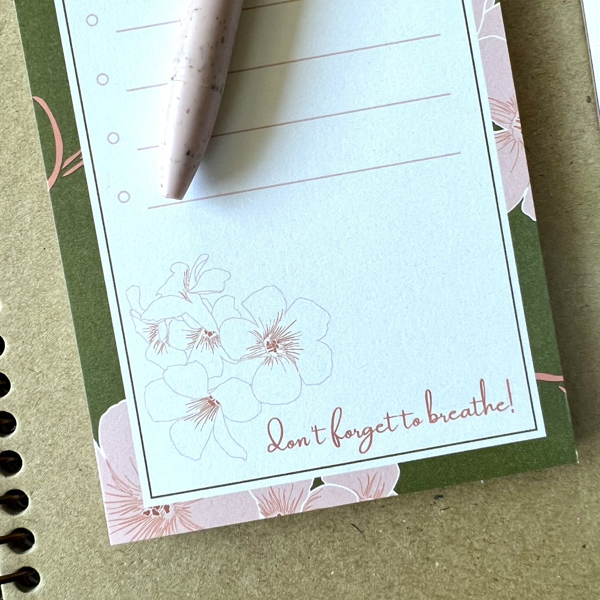 Detail of the bottom of the notepad, where is says don't forget to breathe with a floral sketch illustration