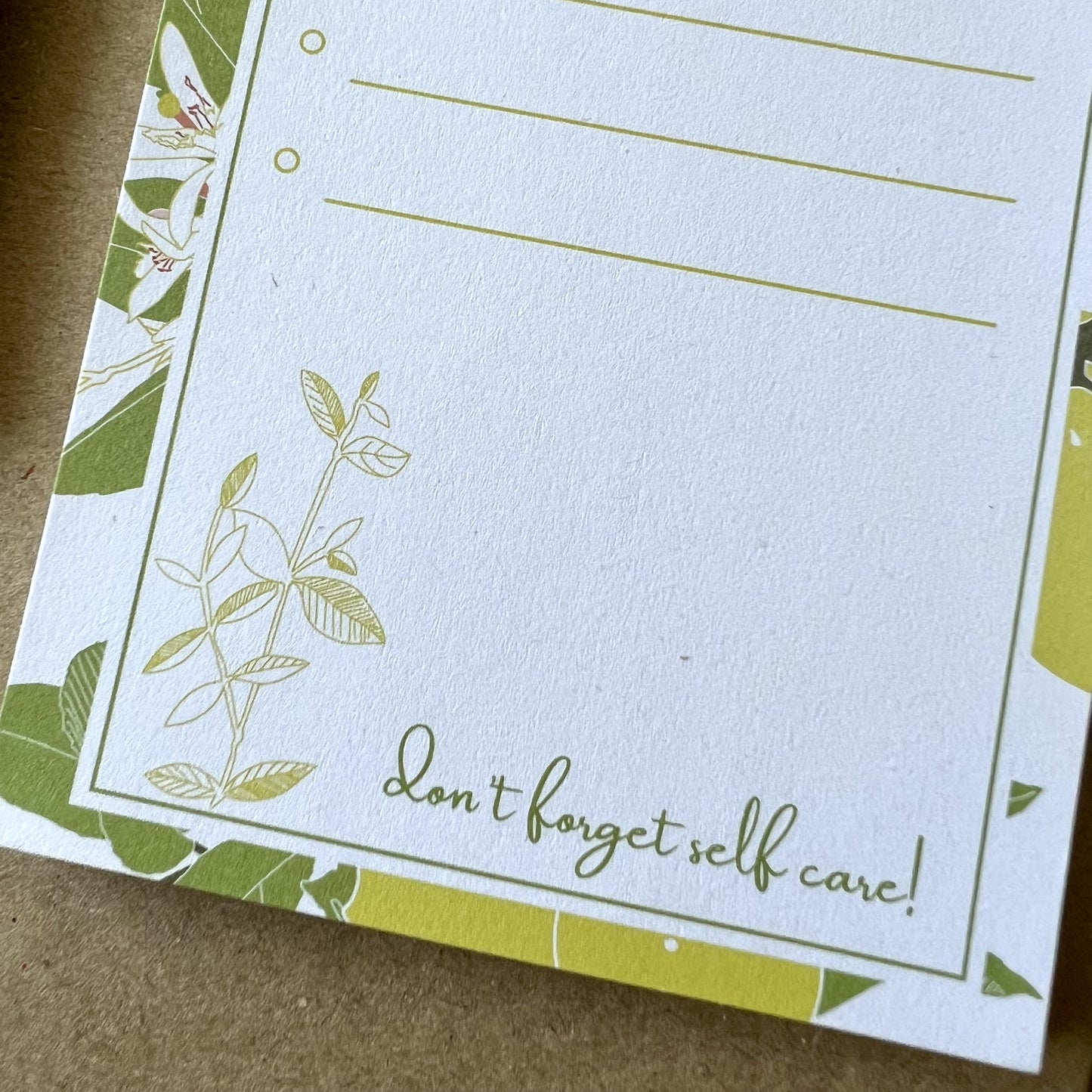 Detail of the bottom of the notepad, which reads don't forget self care with a sketch of a branch and leaves
