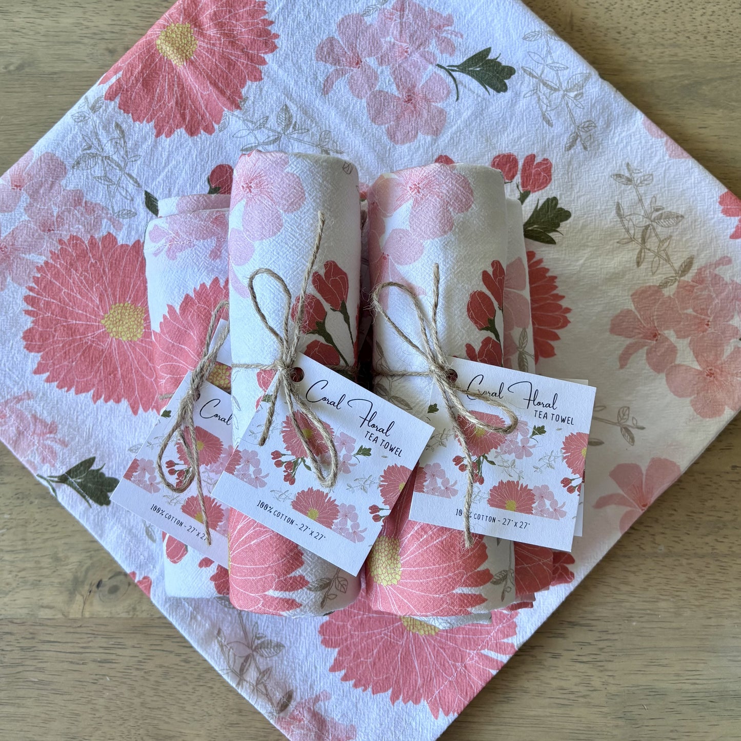 Stack of rolled up pink floral tea towels, tied with twine and square printed hang tags