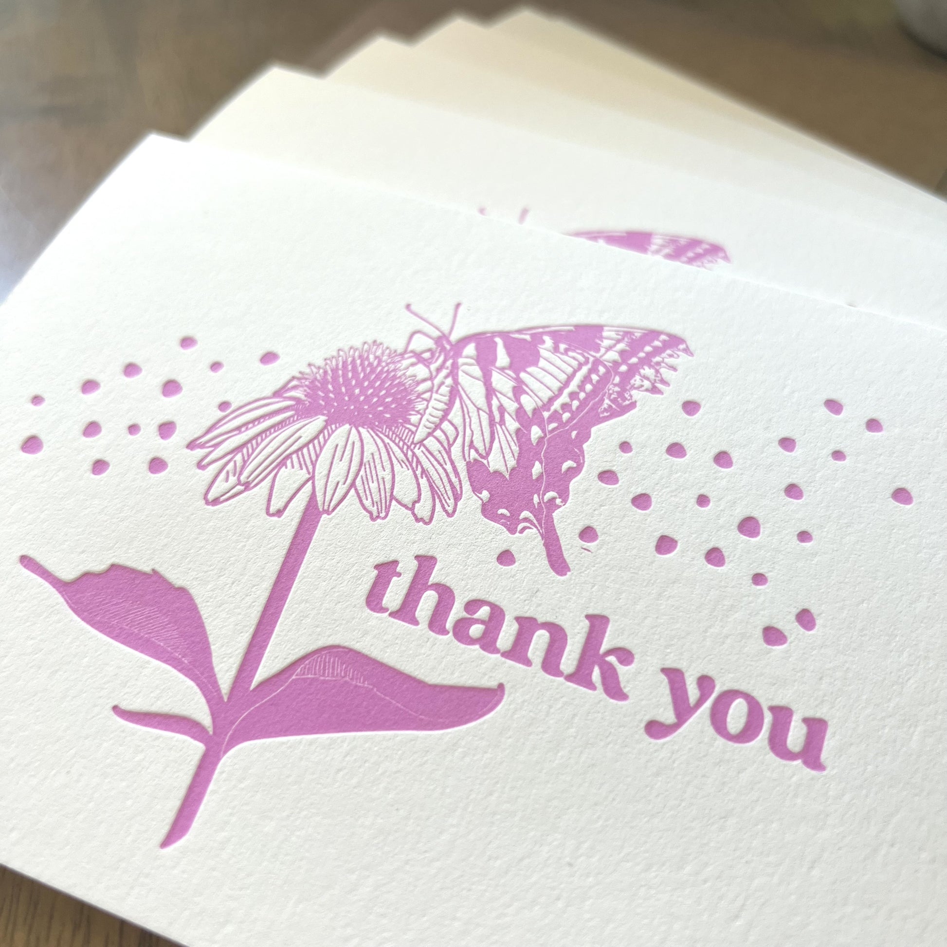 Close up shot of pink butterfly thank you cards, showing the thick texture of the paper and de-bossed letterpress imprint