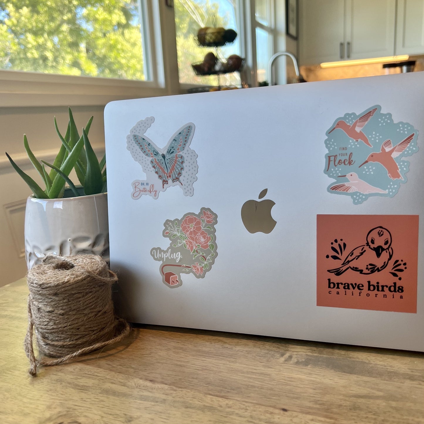 Open laptop with several stickers, including this "find your flock" hummingbird sticker