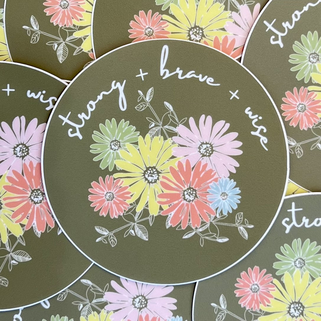 Pile of circular stickers, olive green background, colorful daisy illustration and the words "strong + brave + wise" in white script text
