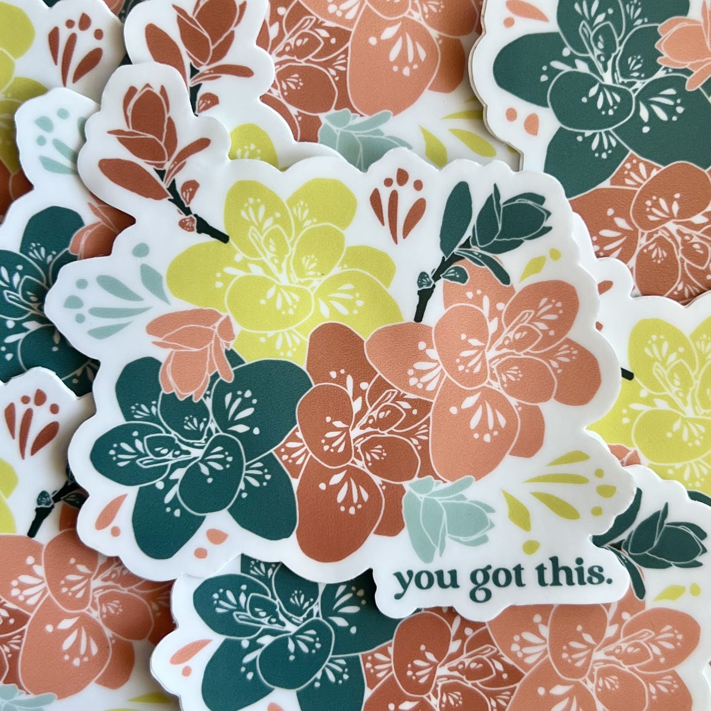 pile of stickers featuring a floral illustration in pink, teal and yellow with the words "you got this."