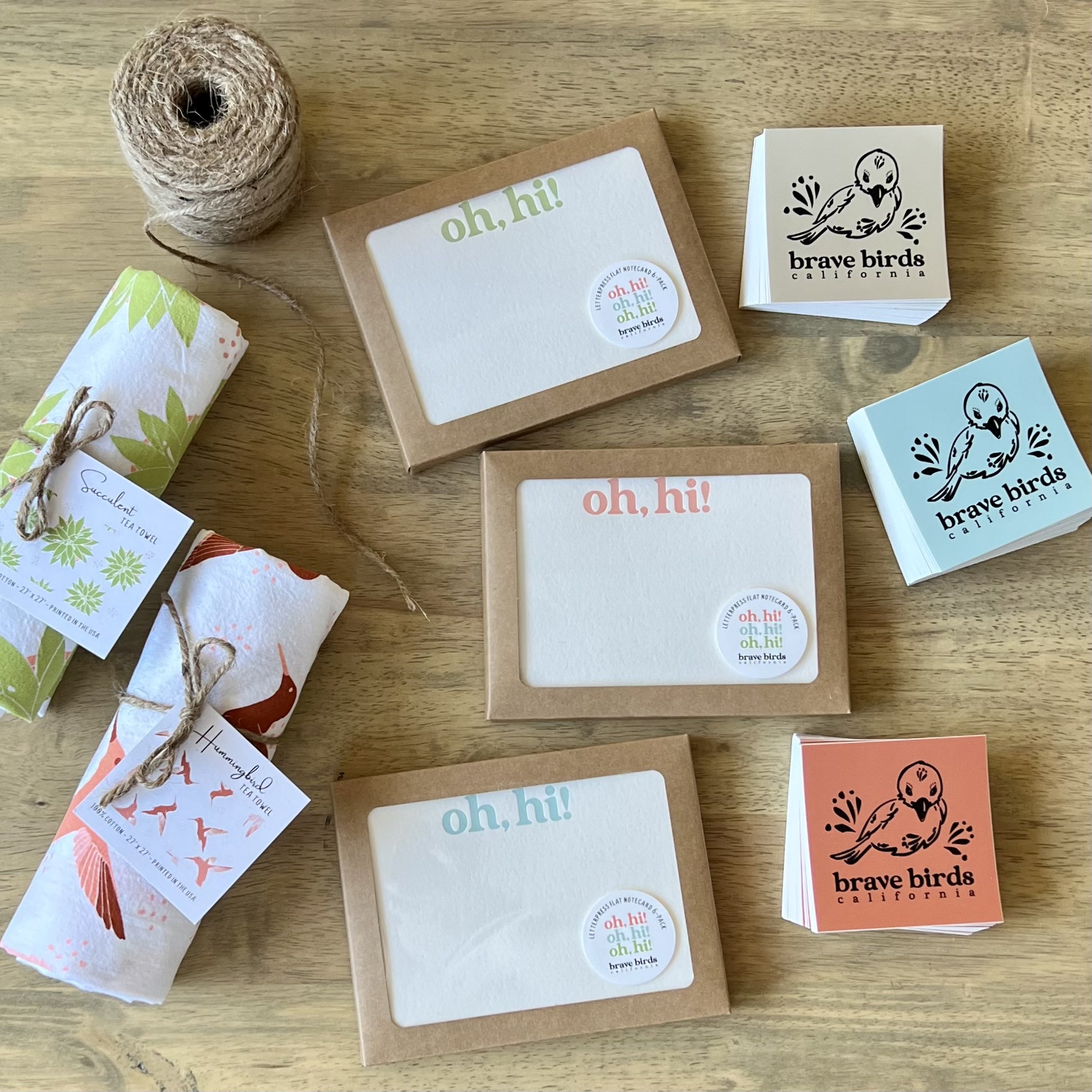 3 boxes of letterpress notecards, styled with Brave Birds stickers and tea towels