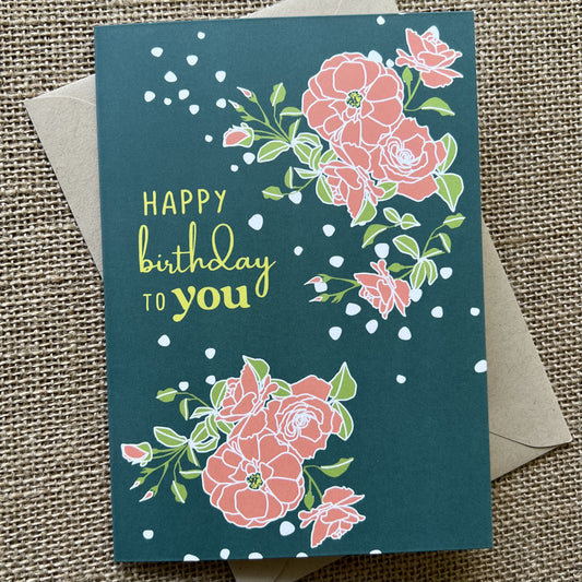 Teal background with pink flowers and "Happy birthday to you" in citron yellow, with a kraft paper envelope