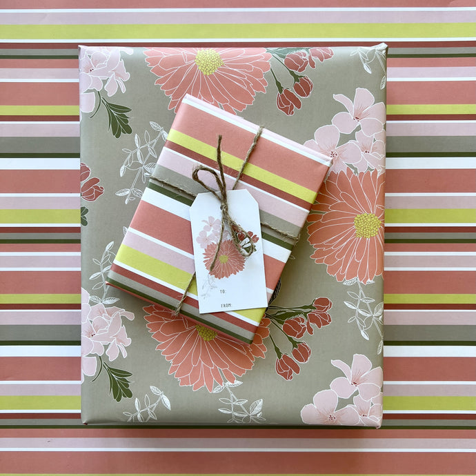 Two gift boxes, one wrapped in coral floral pattern, one wrapped in warm stripe, tied with twine and topped with a floral gift tag