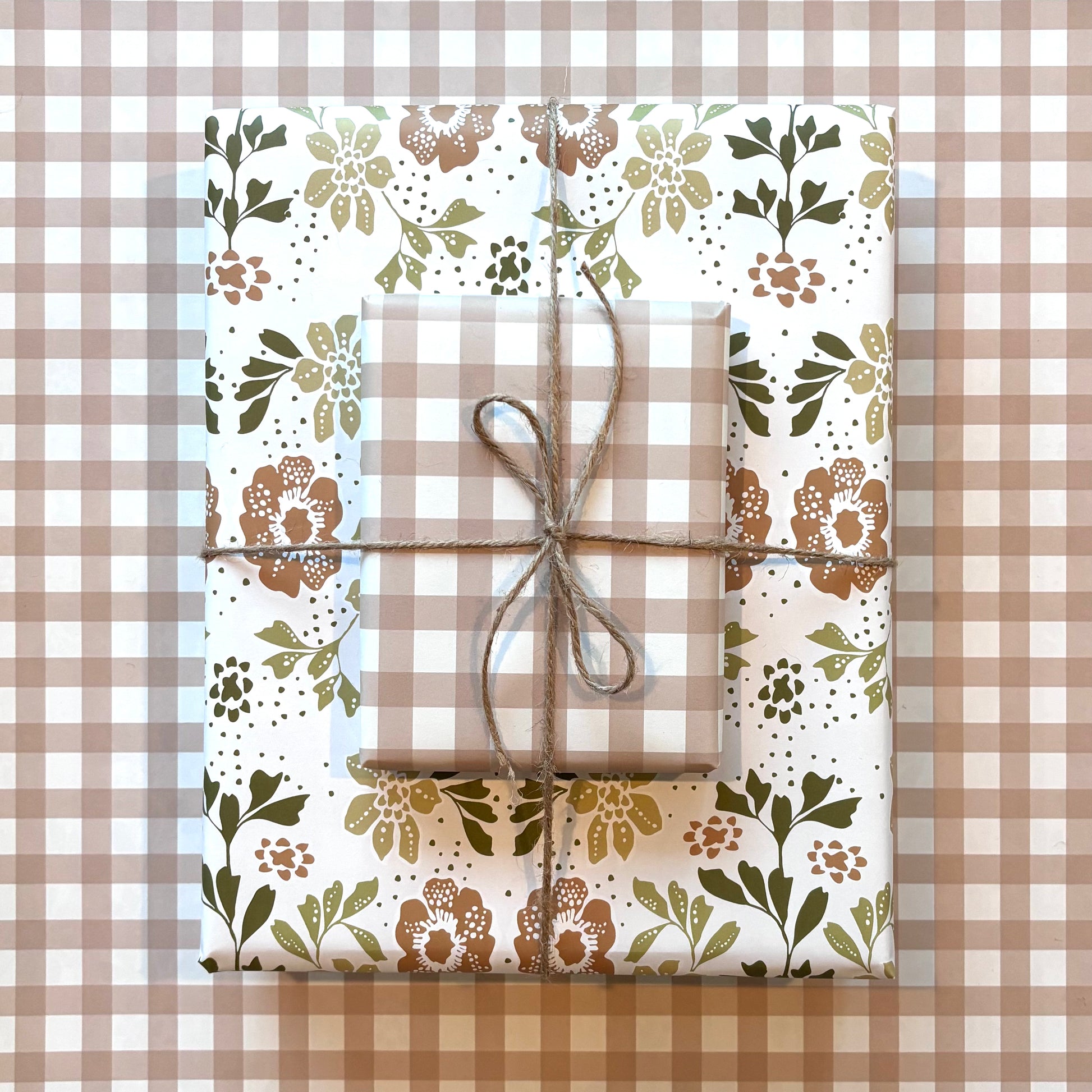 Two gift boxes with tan and cream floral and gingham plaid wrapping paper, tied with twine