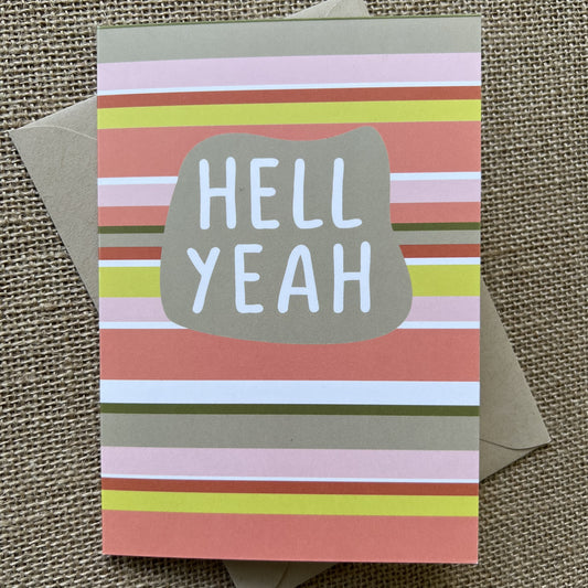 Warm colored horizontal stripes with an organic shape and the words "hell yeah" in white type, shown with a kraft paper envelope