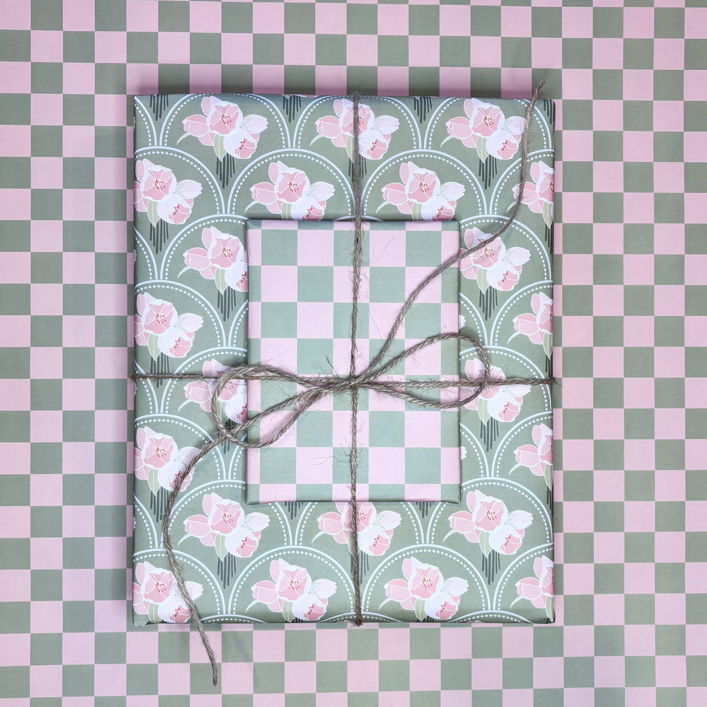 Two wrapped presents with floral patterns on a checkered pink and green background