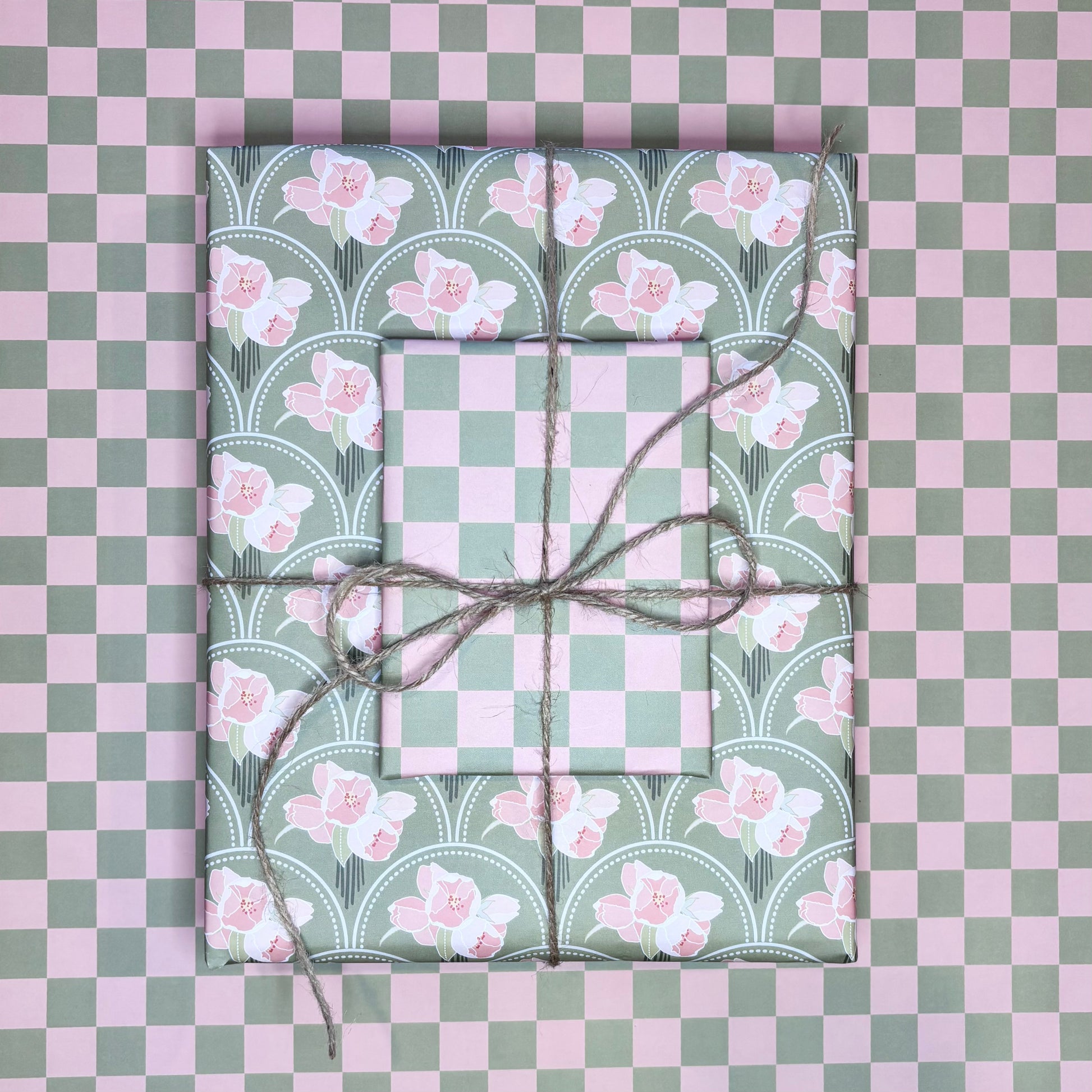 Two wrapped presents with floral patterns on a checkered pink and green background