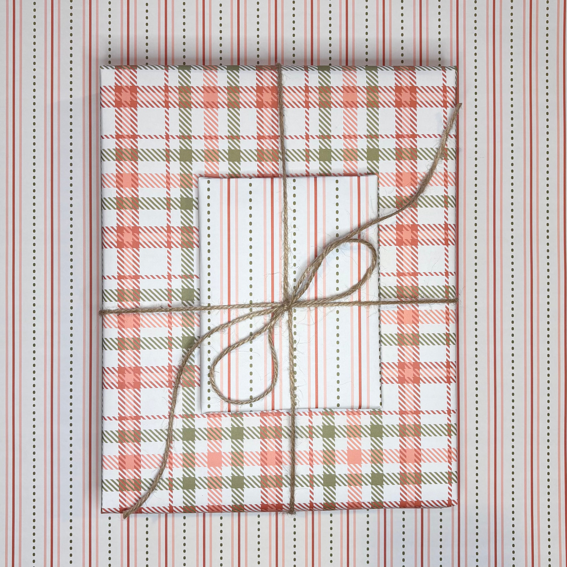 Gift boxes wrapped in plaid patterned paper with twine on a striped background