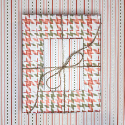 Gift boxes wrapped in plaid patterned paper with twine on a striped background