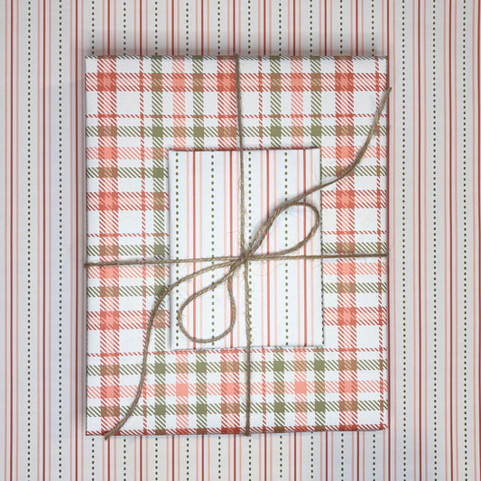 Gift boxes wrapped in plaid patterned paper with twine on a striped background