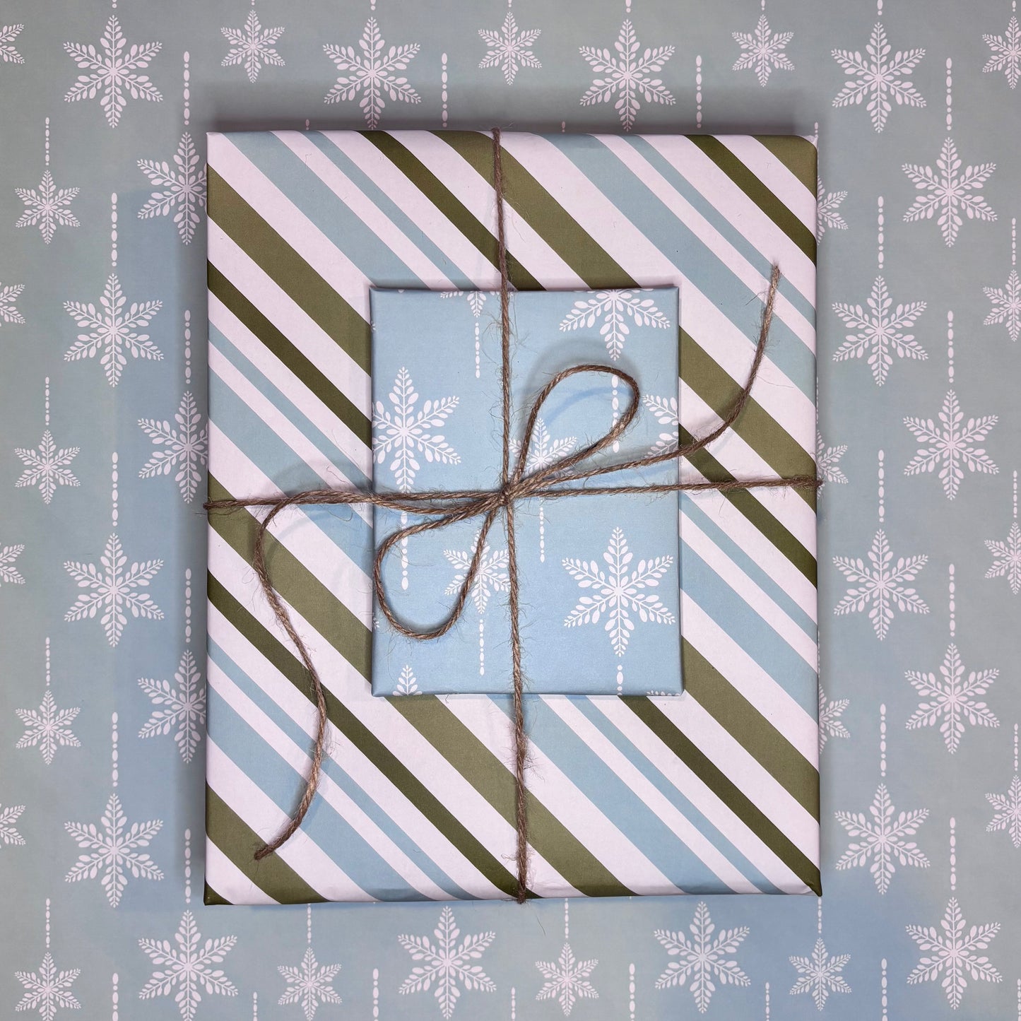 Gift box with striped paper and twine on a blue background with snowflake patterns