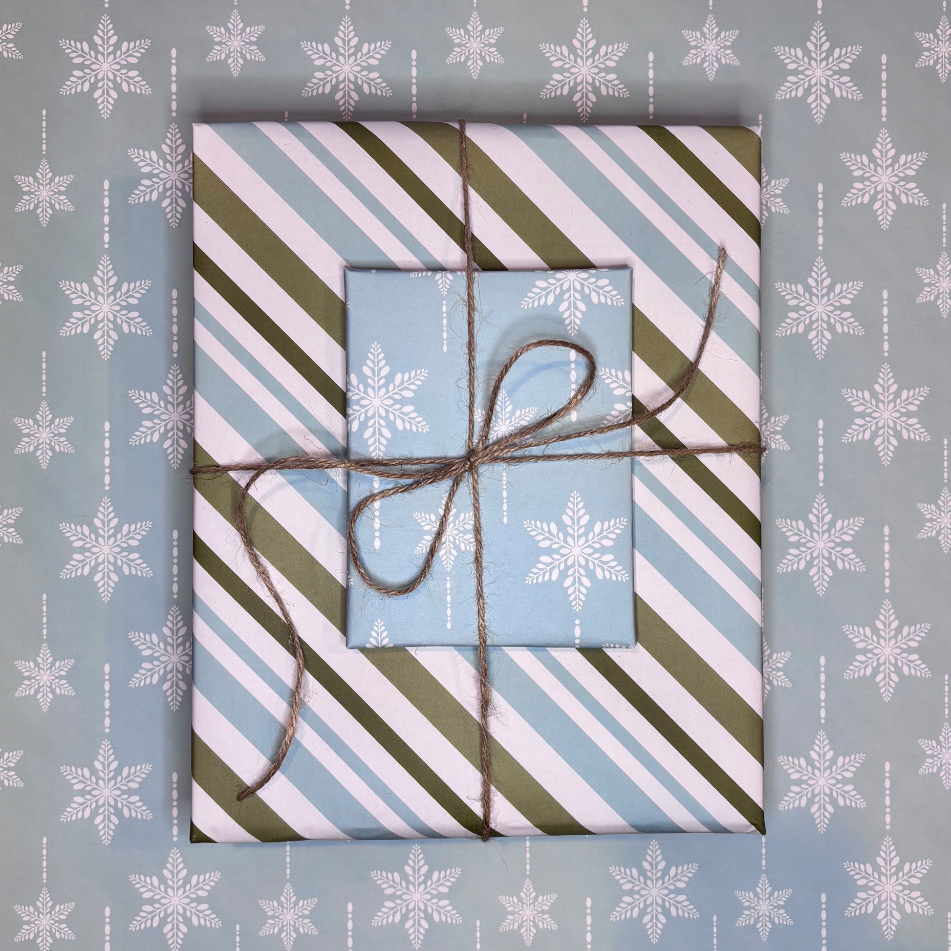 Gift box with striped paper and twine on a blue background with snowflake patterns