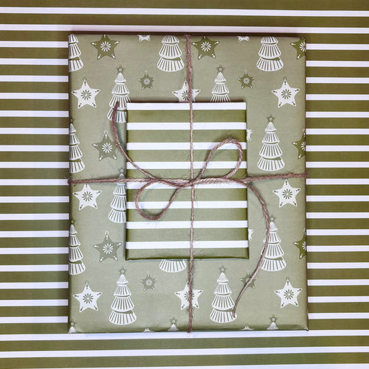 Gift wrapped in green paper with white tree and star pattern, tied with brown string on a striped background.