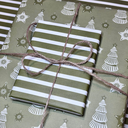 Gift wrapped in green and white striped and Christmas tree paper with twine on a matching background.