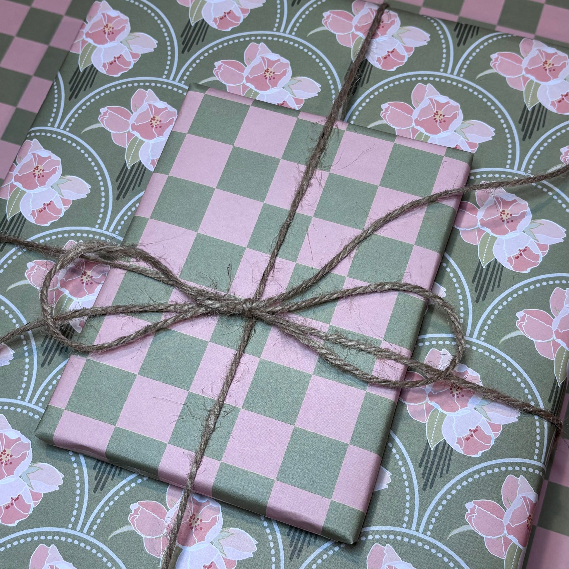 Gift boxes wrapped in pink and green check and floral wrapping paper tied with brown twine