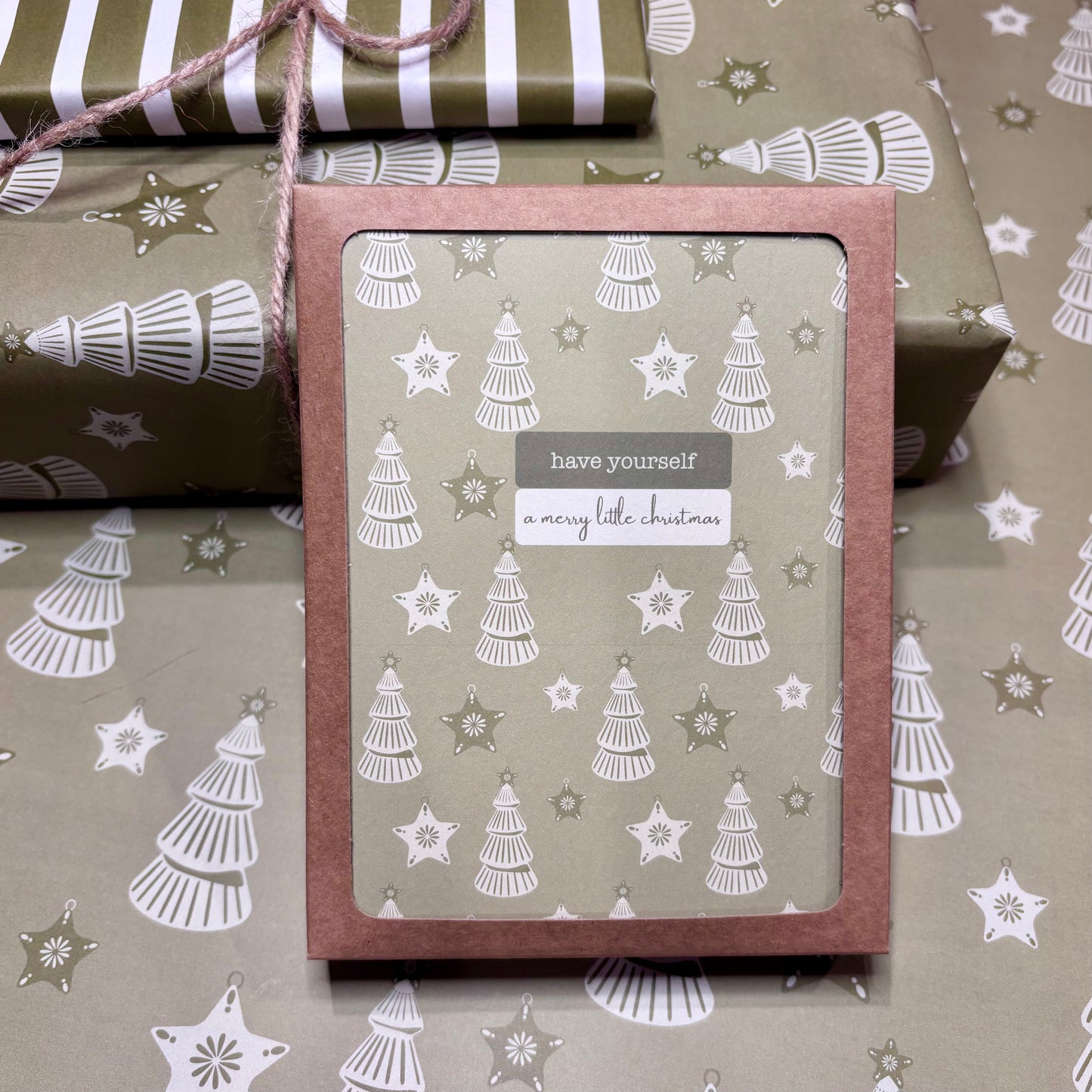 Box of greeting cards with Christmas tree design and text 'have yourself a merry little Christmas' on patterned paper.