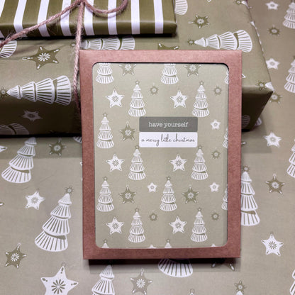 Box of greeting cards with Christmas tree design and text 'have yourself a merry little Christmas' on patterned paper.