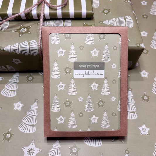 Box of greeting cards with Christmas tree design and text 'have yourself a merry little Christmas' on patterned paper.