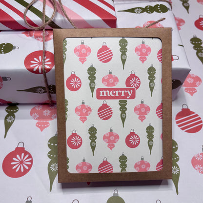 Card with Christmas ornament pattern and 'merry' text, surrounded by wrapped gifts.