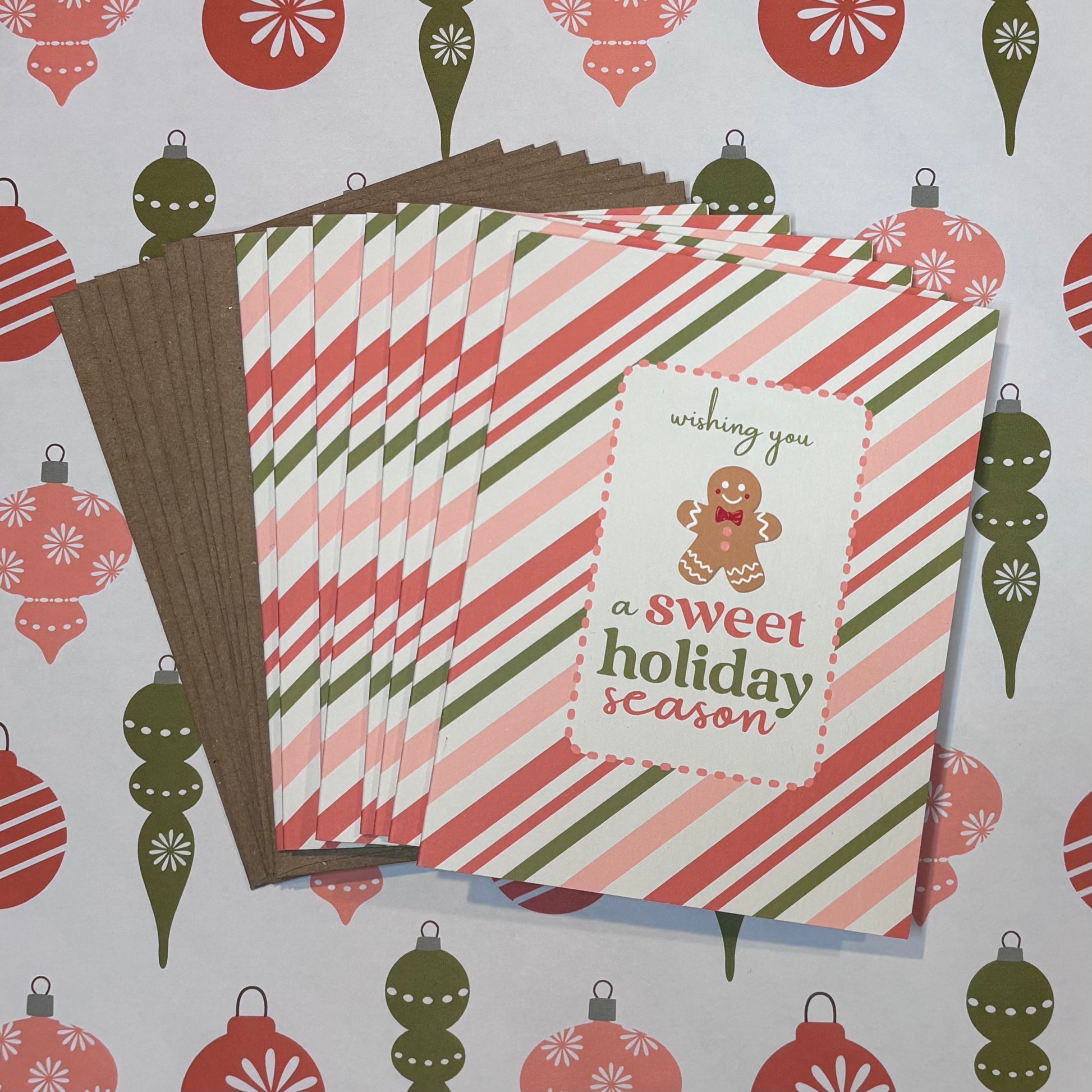 Stack of greeting cards with a gingerbread man design on a decorative background with Christmas ornaments.