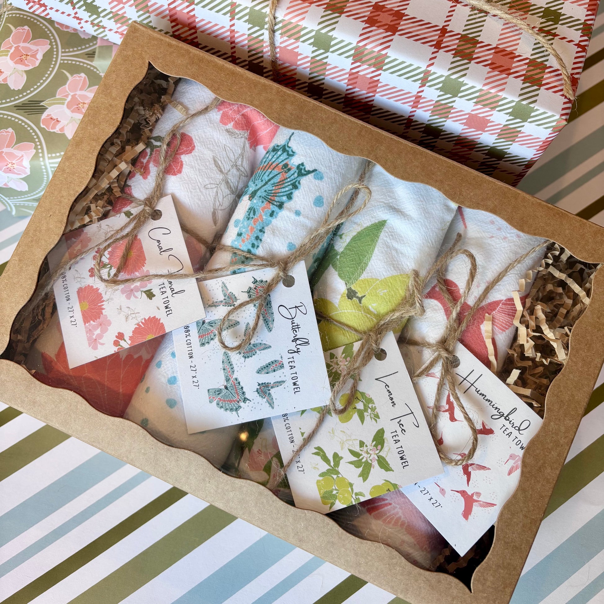 Box of assorted rolled towels with gift tags  on a background of gift wrap