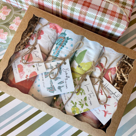 Box of assorted rolled towels with gift tags  on a background of gift wrap