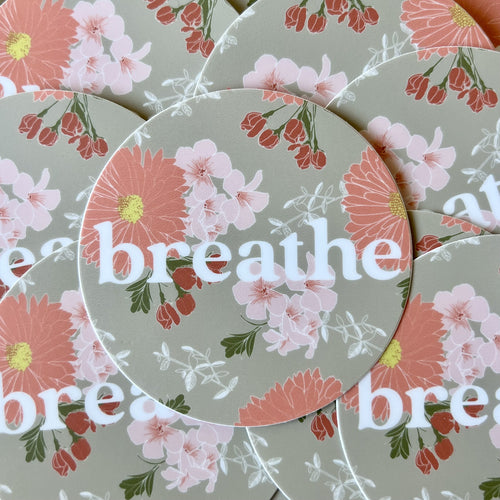 Round khaki sticker with pink floral print and the word breathe in white ink