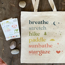 Load image into Gallery viewer, Get Outside Tote in rainbow colored ink shown styled with our California sticker sheet, in similar bright rainbow colored text.
