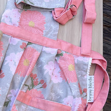 Load image into Gallery viewer, Zoomed in detail shot of apron trim: pleating at the waist, coral pink trim, woven label reading &quot;brave birds california&quot; and white scalloped fabric edging
