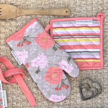 Load image into Gallery viewer, Floral printed oven mitt in pink &amp; khaki with a color-coordinated striped square potholder, both with hanging loops, styled with a wooden spoon and heart shaped cookie cutters
