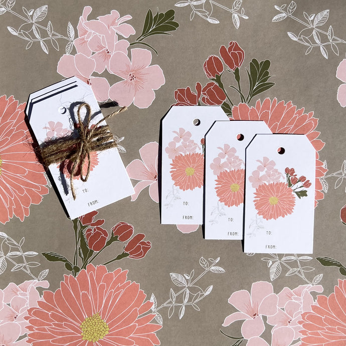 gift tag 3 pack with coral floral design, shown tied with twine laying on coordinating wrapping paper