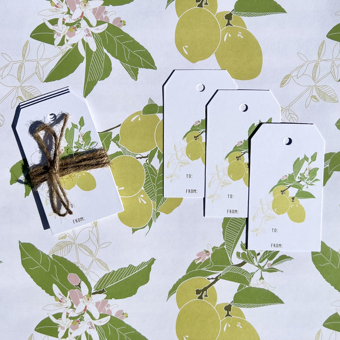 gift tag 3 pack with lemon tree design, shown tied with twine laying on coordinating wrapping paper